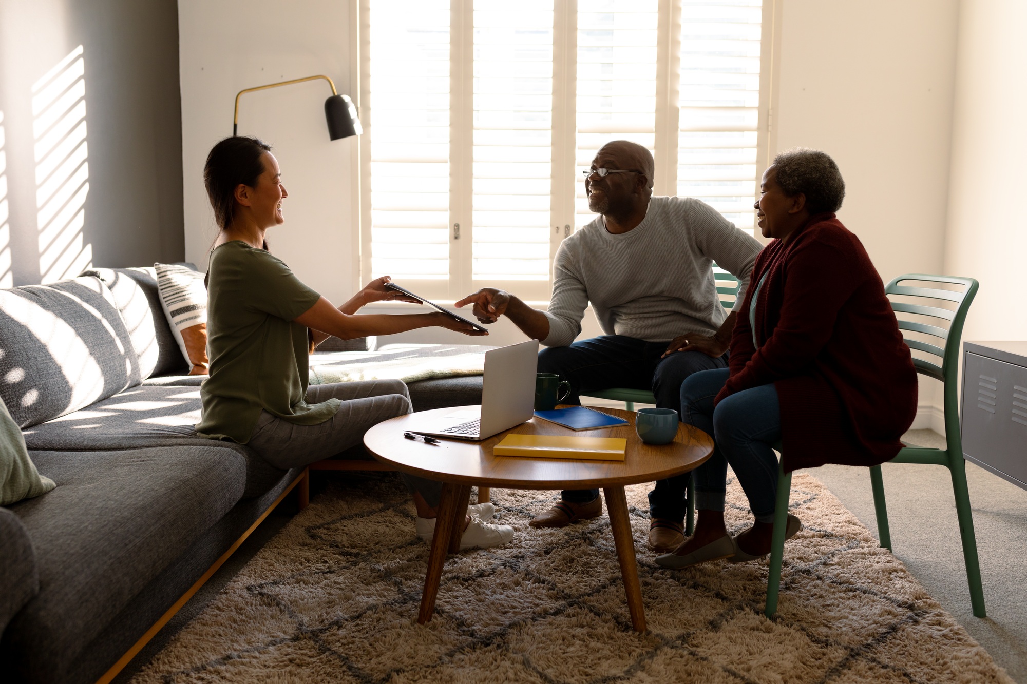 African american senior couple having meeting with asian female financial advisor at home